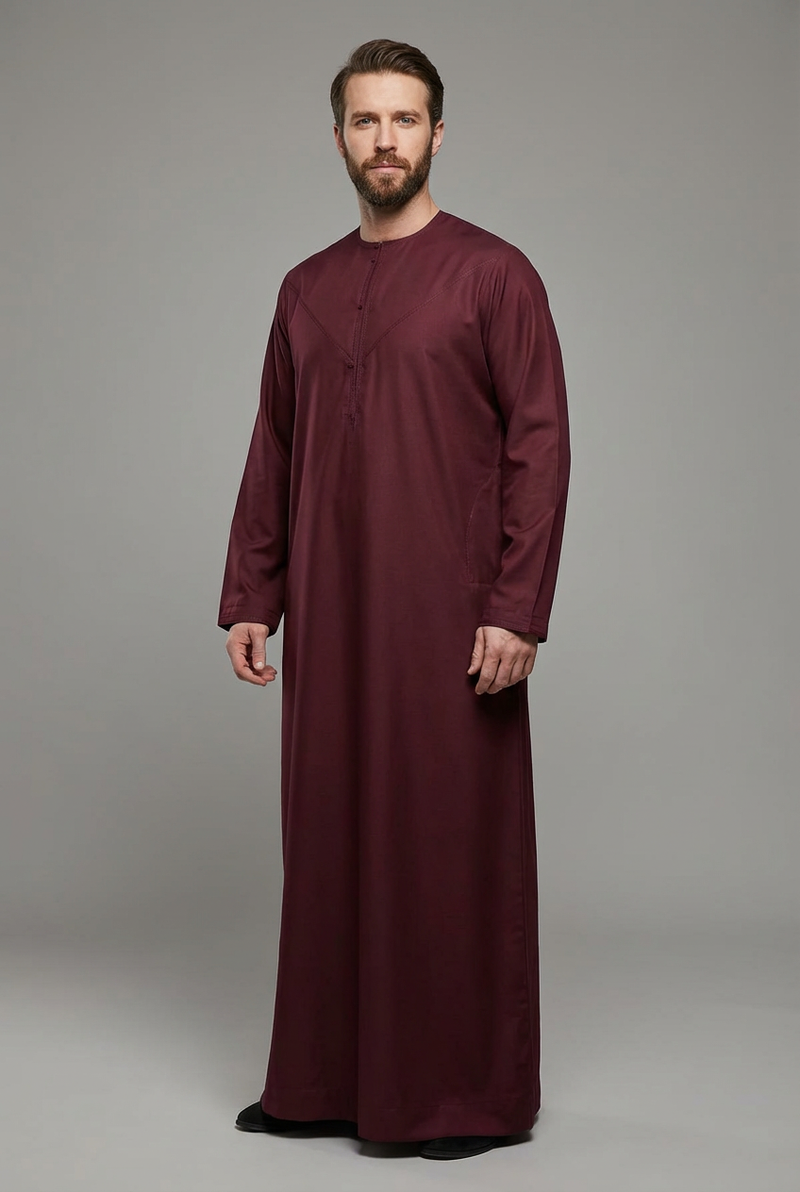 Model wearing a burgundy Omani thobe with tonal neckline stitching.