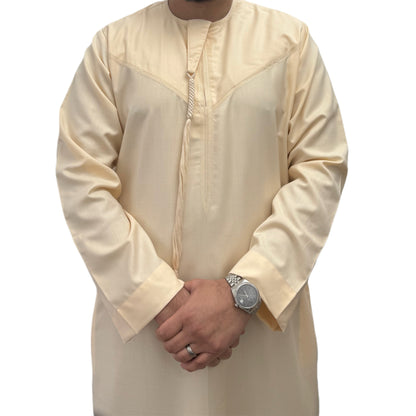 Man wearing a plain Cream Omani thobe with hands crossed, featuring a relaxed fit and traditional tassel detail