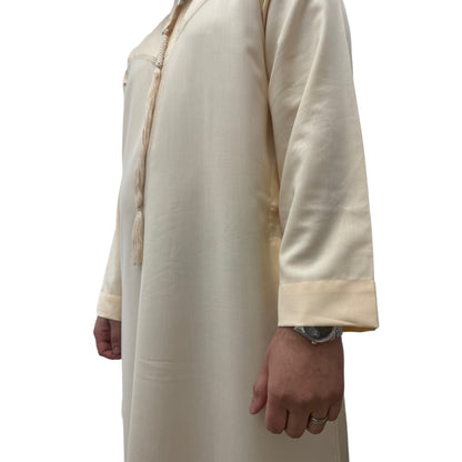 Side view of a man wearing a plain cream Omani thobe, showcasing the relaxed silhouette and traditional detailing