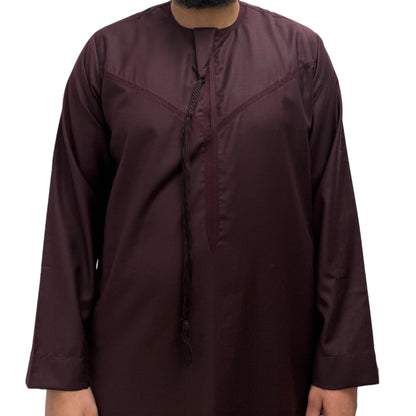 Model standing with hands by his side wearing a Burgundy Omani thobe, minimalist design with clean tailoring