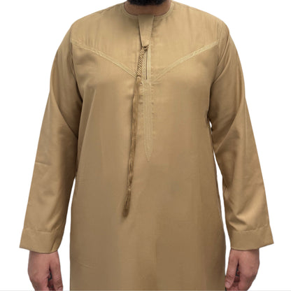 Model standing with hands by his side wearing a Beige Omani thobe, minimalist design with clean tailoring