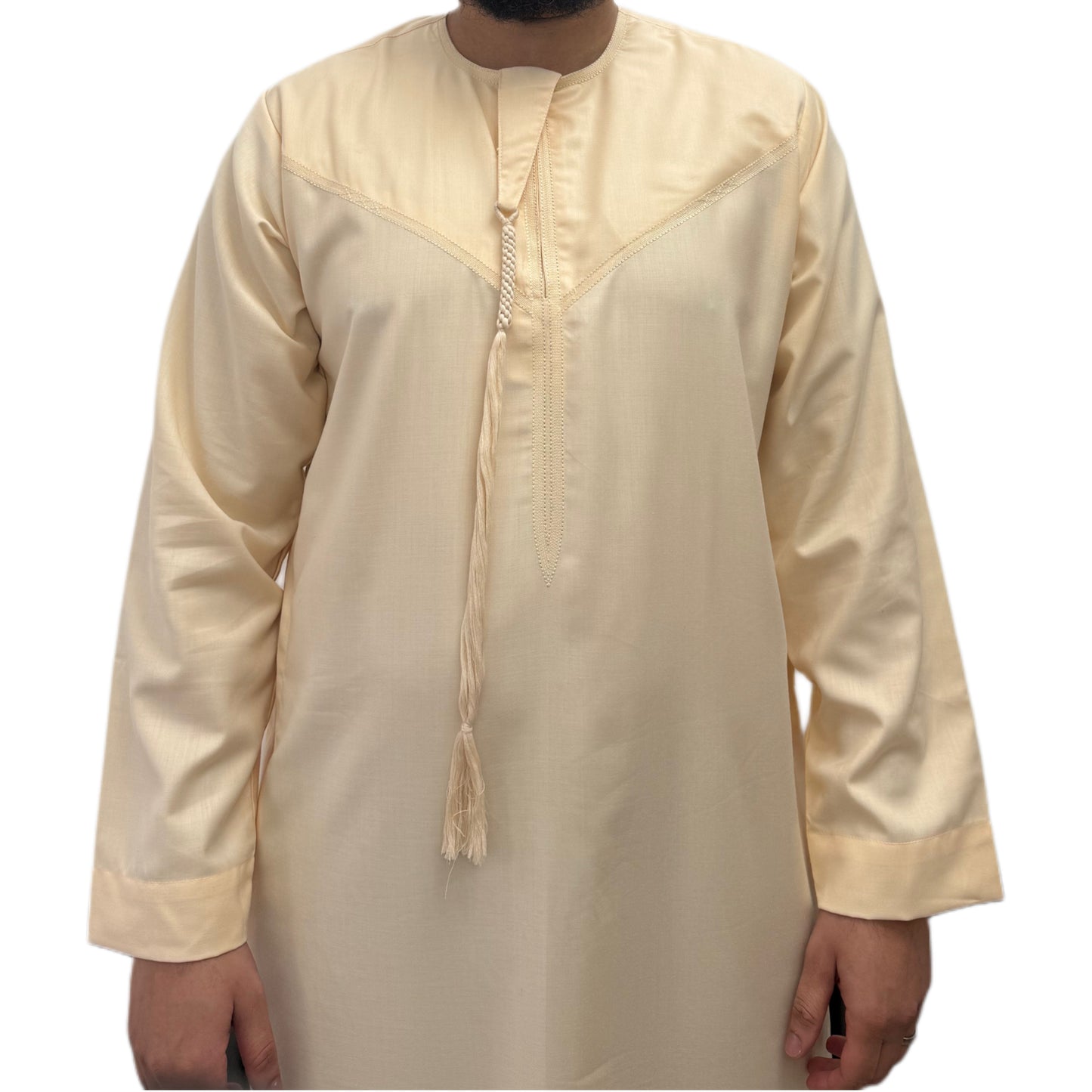 Model standing with hands by his side wearing a cream Omani thobe, minimalist design with clean tailoring