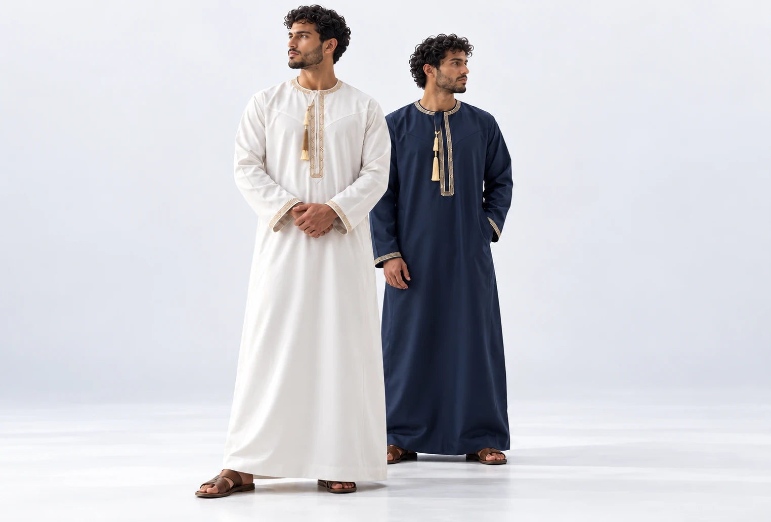 White and navy embroidered Royal Omani thobes, styled in a light studio